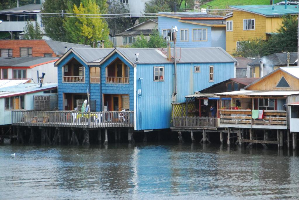 a blue house on a dock next to the water at Palafito Azul Apart Hotel in Castro