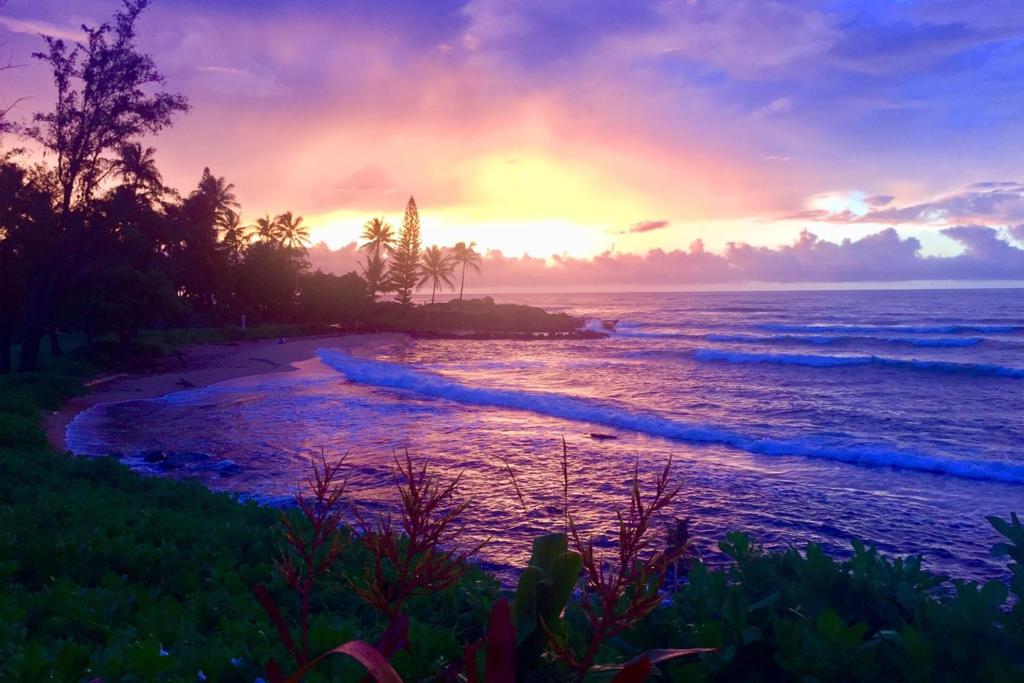 a sunset on a beach with the ocean at Lanikai Condos in Kapaa