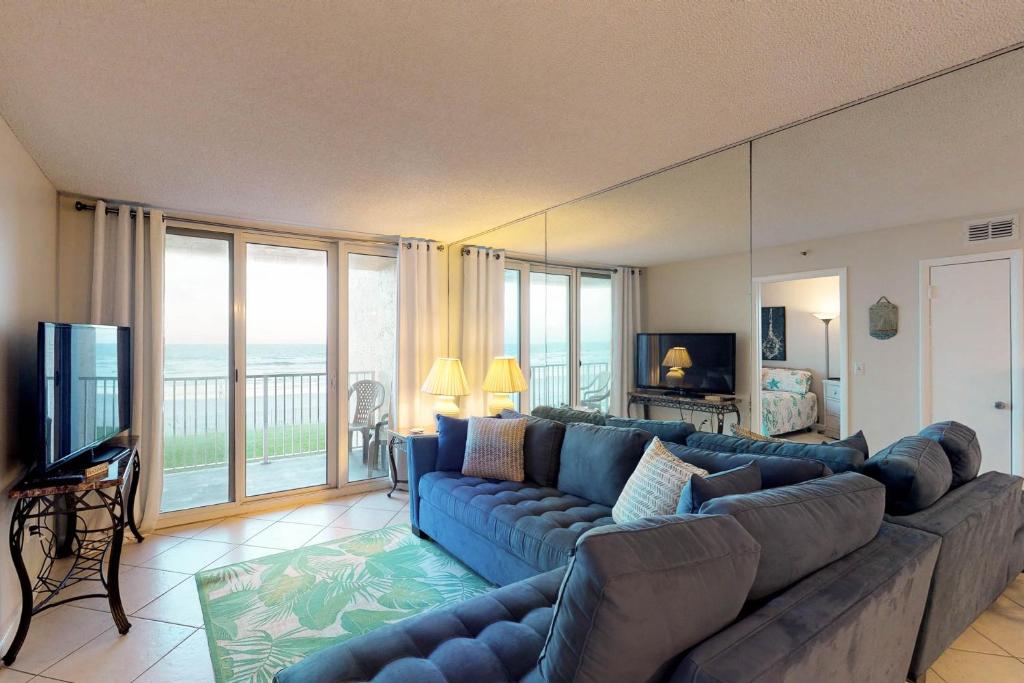 a living room with a blue couch and a television at Oceania Plaza & Suites in New Smyrna Beach