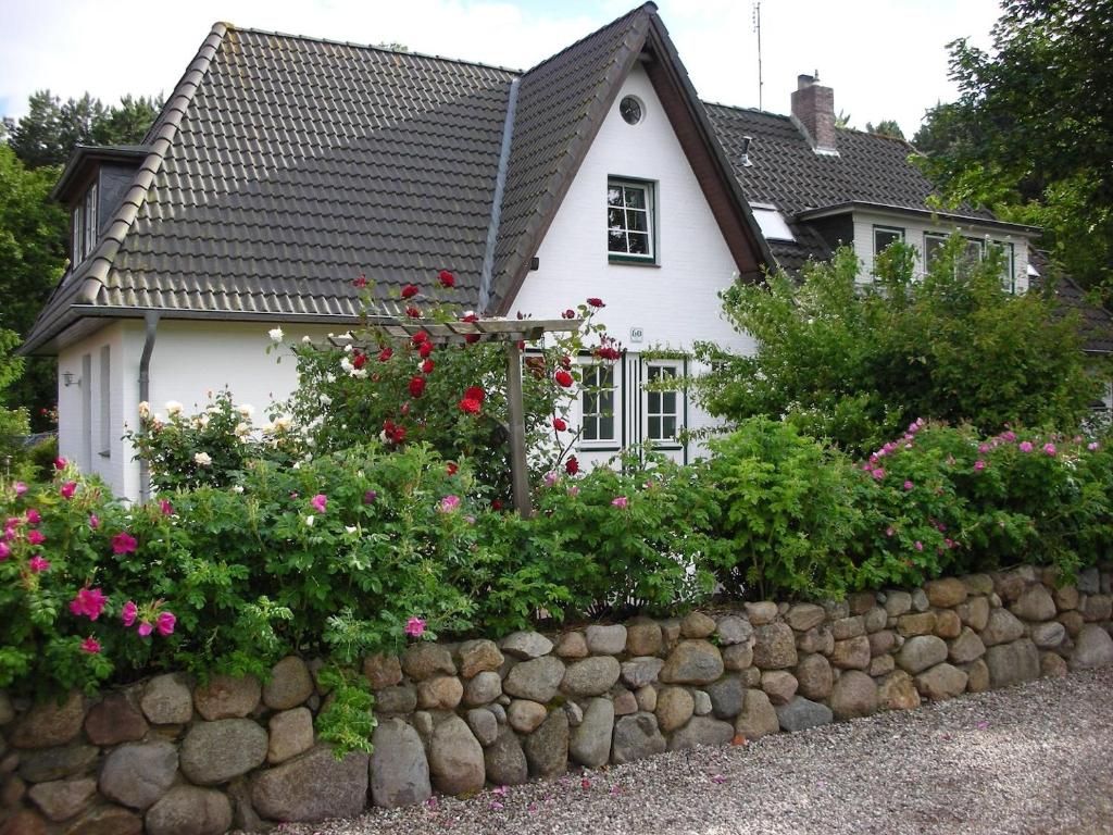 a house with flowers in front of a stone wall at Ferienwohnungen Outzen in Nebel