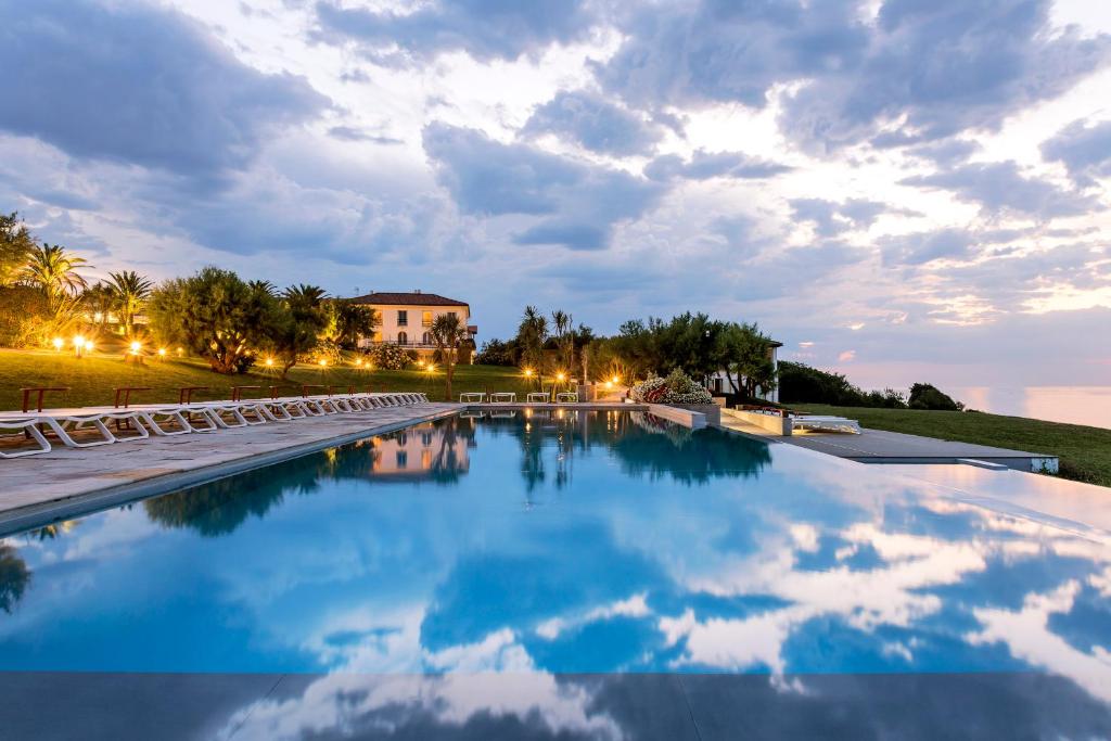 a swimming pool with chairs and a building in the background at Hôtel La Réserve in Saint-Jean-de-Luz