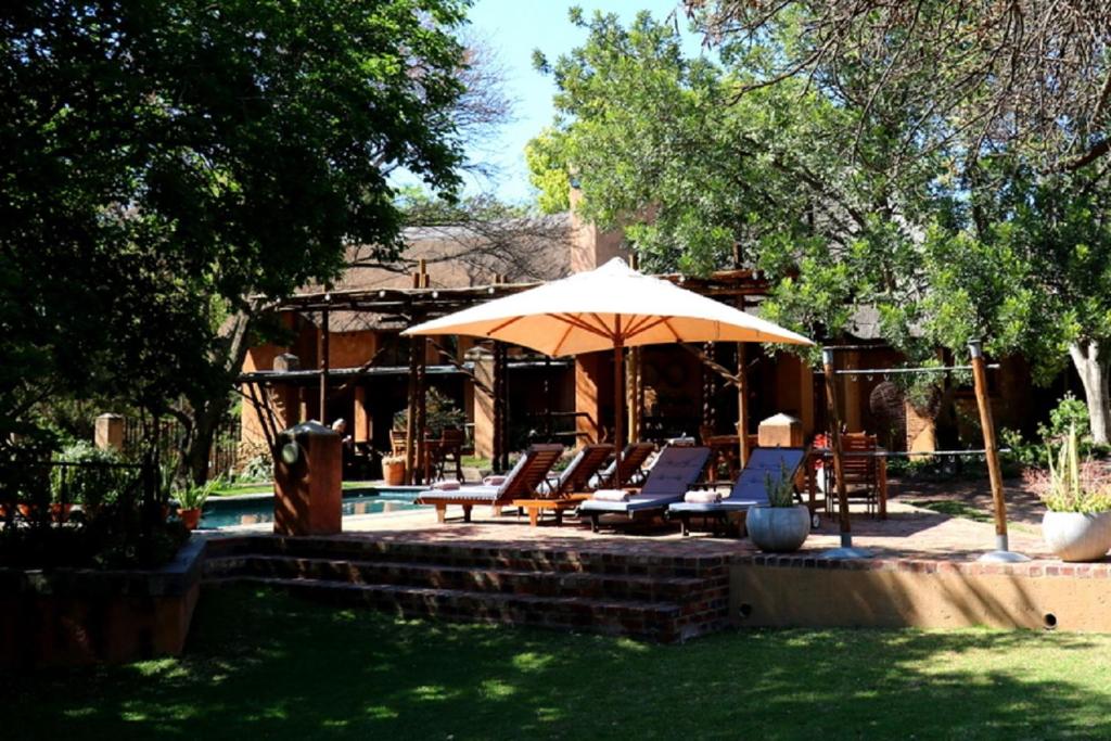 um grupo de cadeiras e um guarda-sol junto a uma piscina em Sherewood Lodge em Pretoria