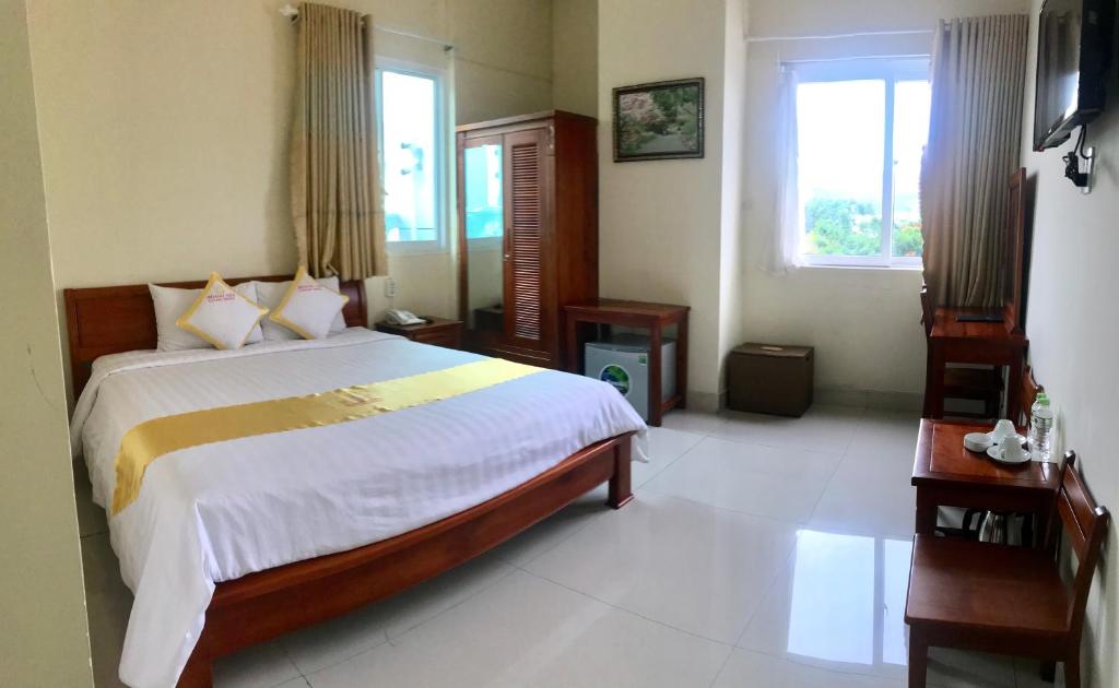 una camera con un grande letto e due finestre di Hoang Yen Canary Hotel a Quy Nhon