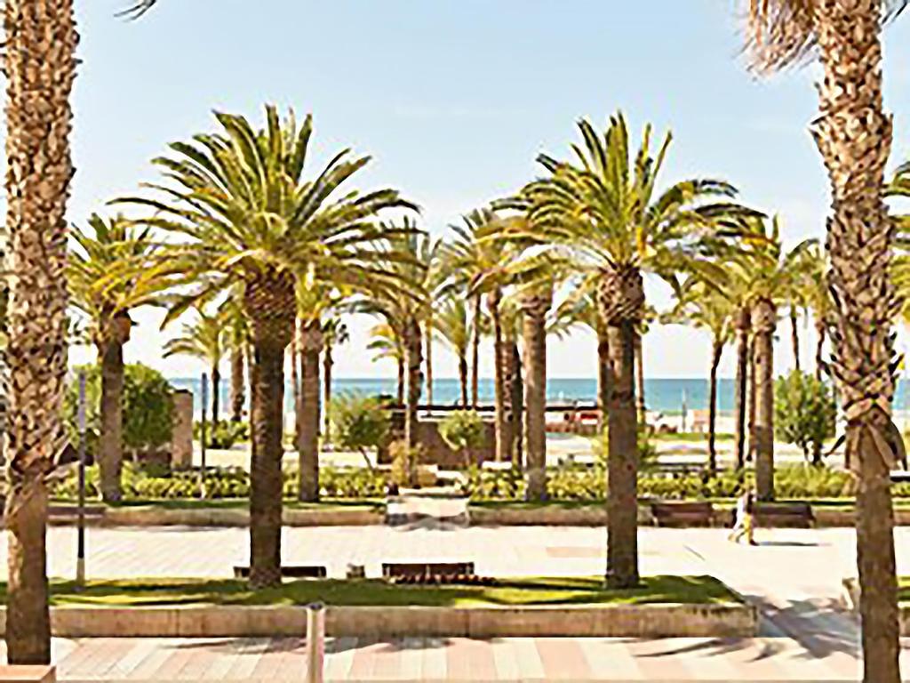 een rij palmbomen in een park met de oceaan bij APARTMENT SALOU MAIN BEACH in Salou