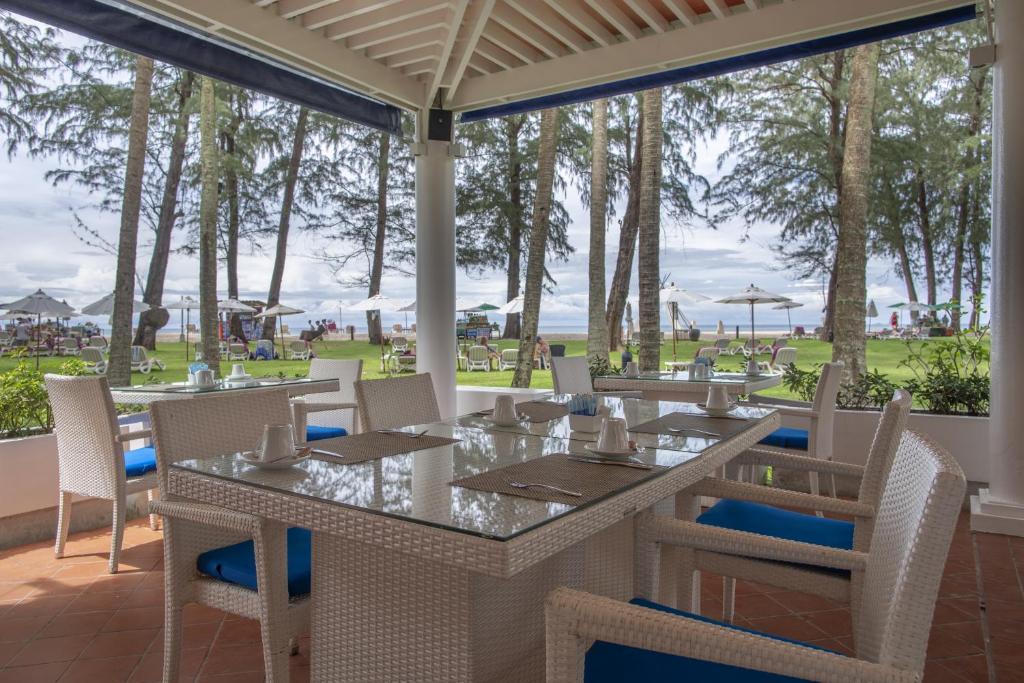 a dining room with tables and chairs and a view of the ocean at Dusit Thani Laguna Phuket in Bang Tao Beach