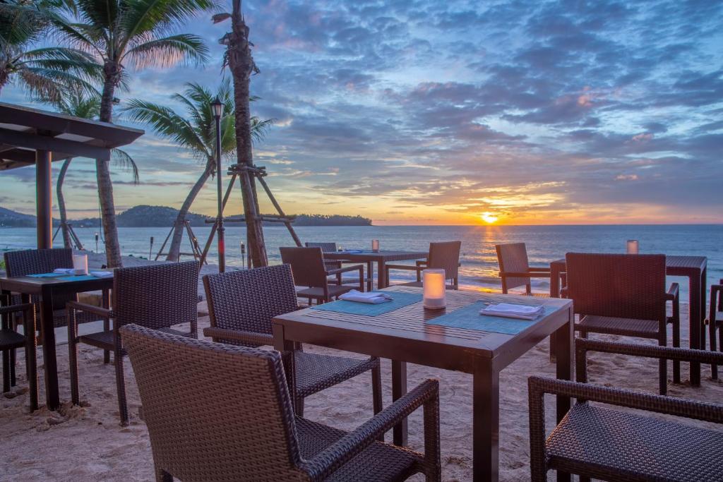 a table and chairs on the beach with a sunset at Dusit Thani Laguna Phuket in Bang Tao Beach