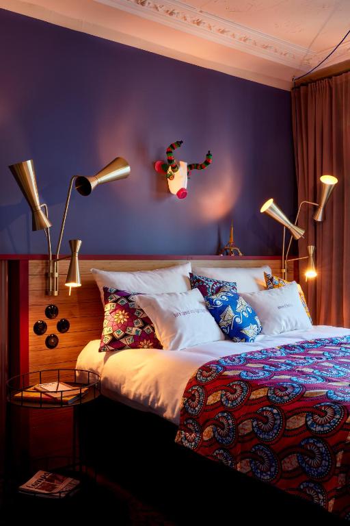 - une chambre avec un grand lit et un mur pourpre dans l'établissement 25hours Hotel Terminus Nord, à Paris