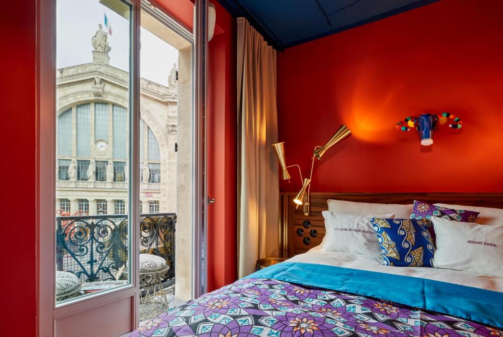 a bedroom with a red wall and a window at 25hours Hotel Terminus Nord in Paris