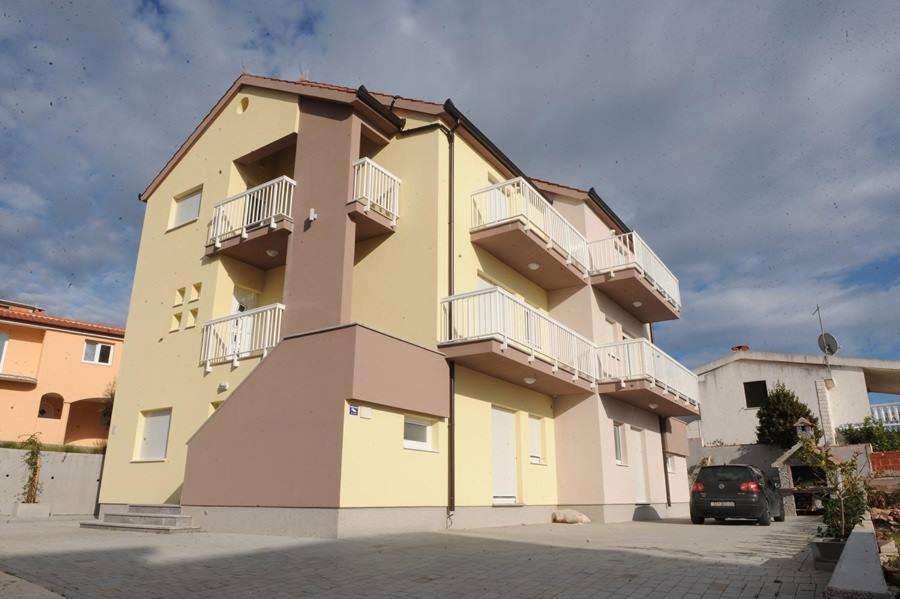 a yellow building with balconies on the side of it at Apartment David in Rogoznica