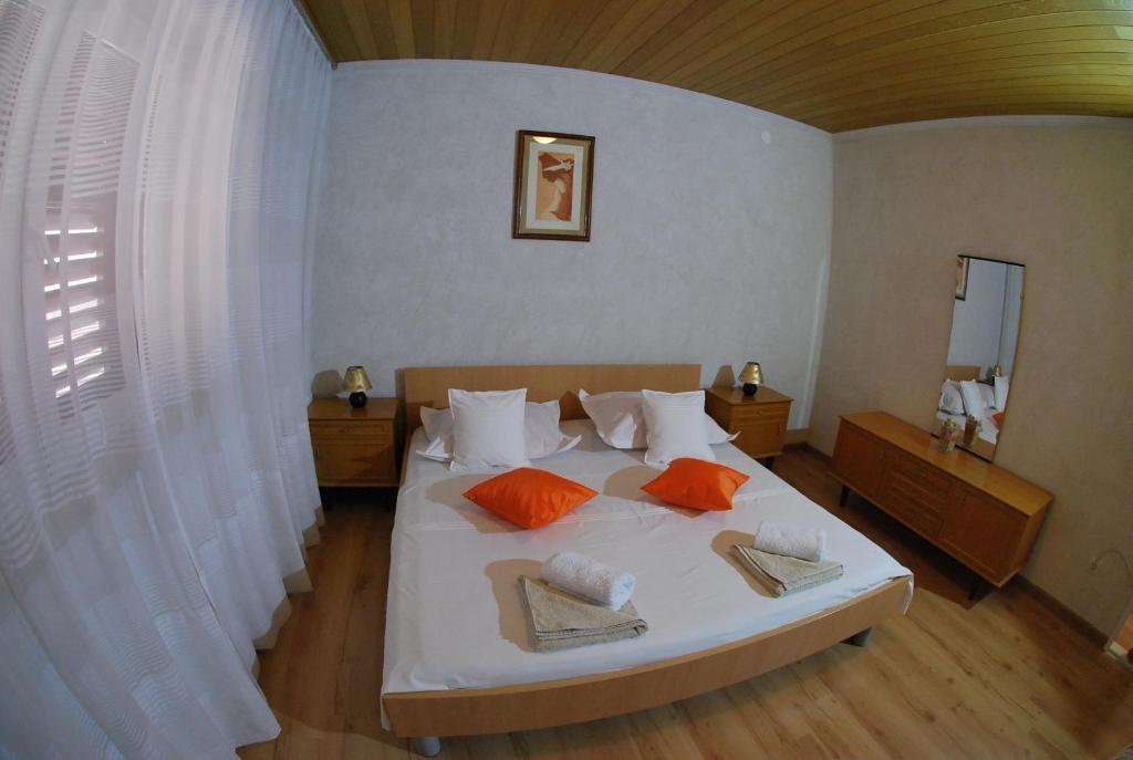 a bedroom with a large white bed with orange pillows at Apartman Ružica in Makarska