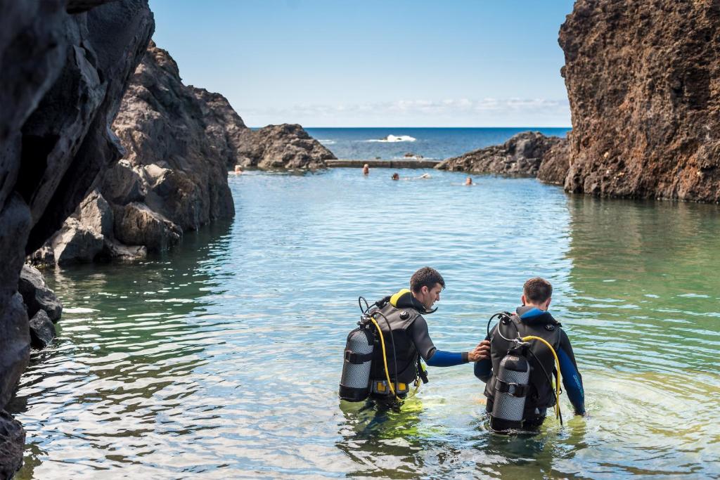 two men in the water in a cave at Aqua Natura Madeira in Porto Moniz