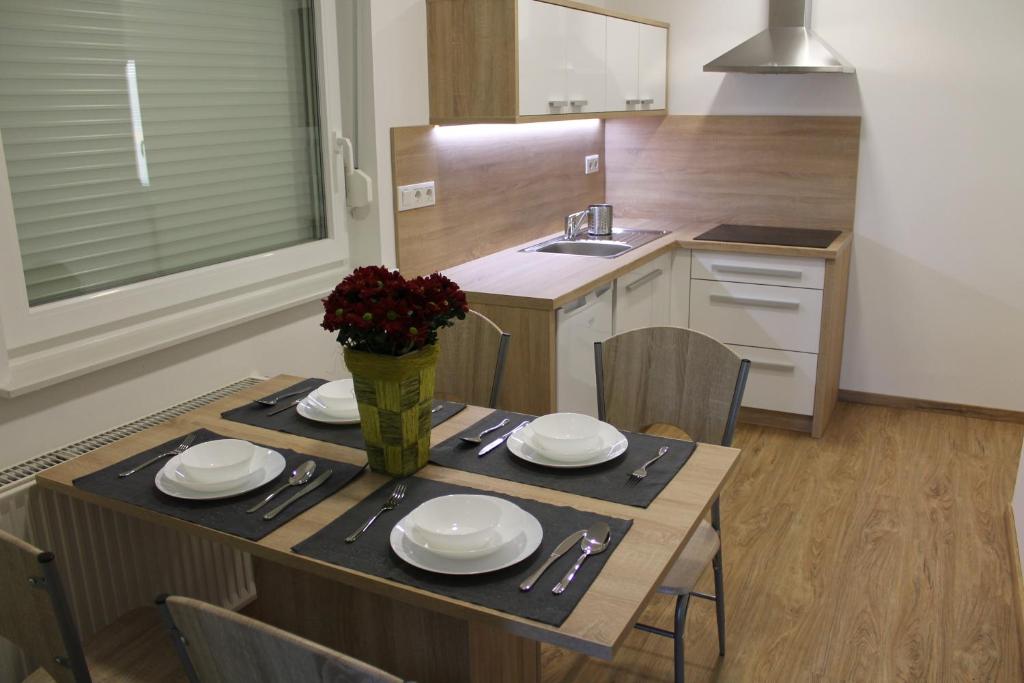 a kitchen with a table with plates and flowers on it at Petite Apartment in Maribor