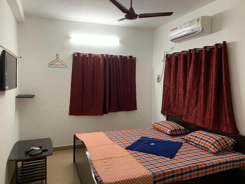 a bedroom with a bed and a window with red curtains at TEMPLE TREE HOMES next to SANKARA NETHRALAYA & APOLLO HOSPITALS in Chennai