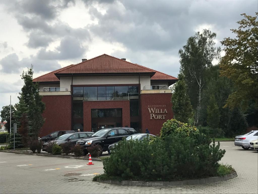 a building with cars parked in front of a parking lot at APARTAMENT 304 Willa Port in Ostróda