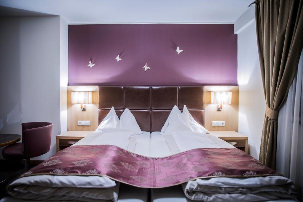 a bedroom with a large bed with a purple wall at Hotel Flair in Salzburg