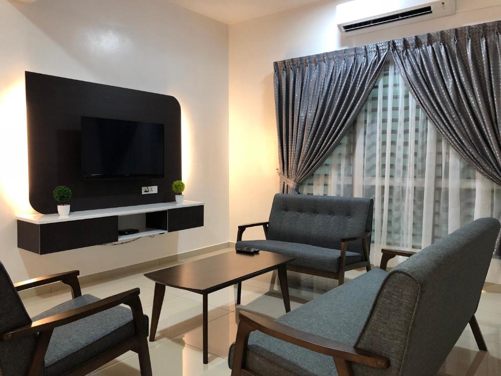a living room with a tv and two chairs and a table at Family homestay in Kuala Selangor