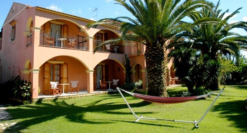 a hammock in front of a house with palm trees at Marios Studios in Sidari