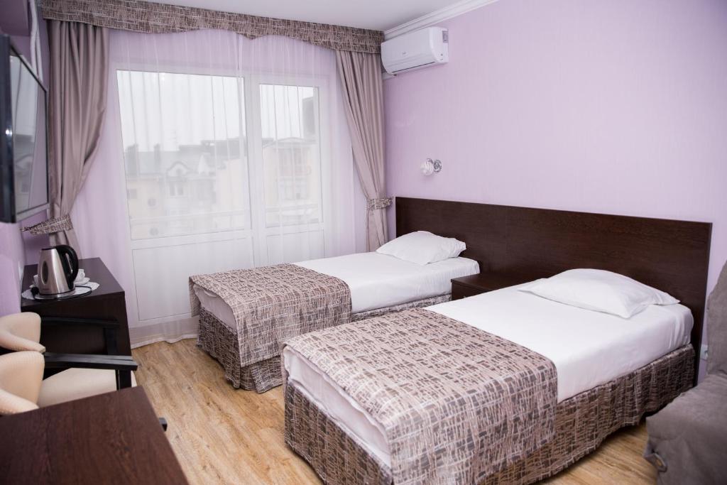 a hotel room with two beds and a window at Pansionat Iskra in Pyatigorsk