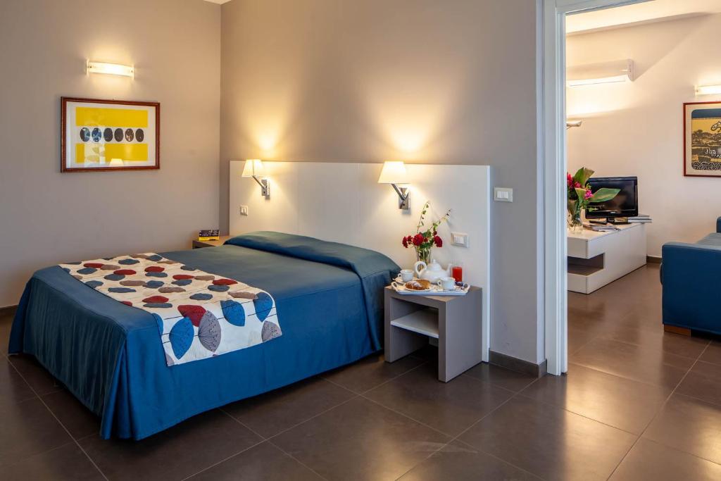 Marbela Apartments & Suites في باليرمو: غرفة نوم بسرير وطاولة وتلفزيون