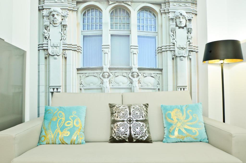 a white couch with pillows in front of a building at NineSuites in Seville