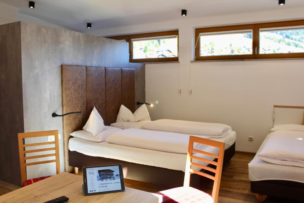 a bedroom with two beds and a desk with a laptop at Pension Norika in Saalbach Hinterglemm