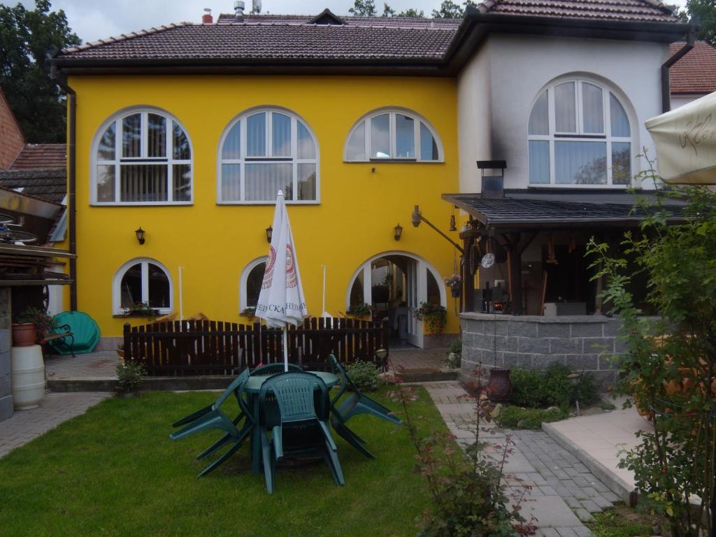 a yellow house with a table and chairs in the yard at Penzion U Urbanů in Němčice