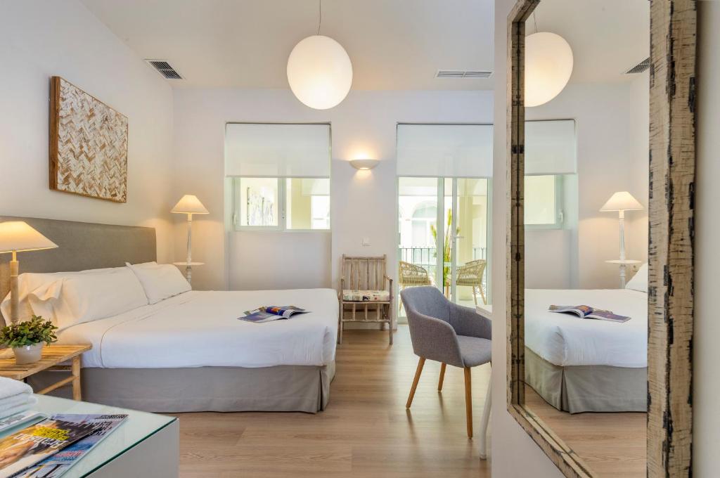 Cette chambre comprend 2 lits et un miroir. dans l'établissement Suites Sevilla Plaza, à Séville