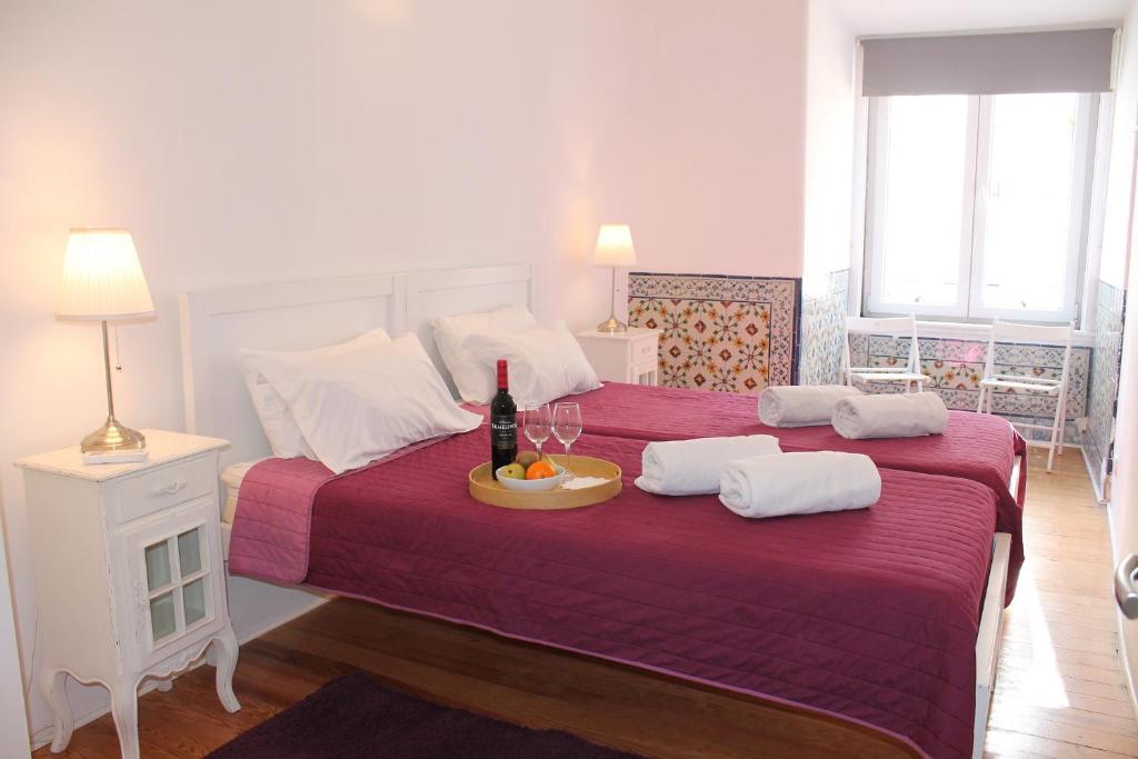 ein Schlafzimmer mit einem großen Bett und einer Flasche Wein darauf in der Unterkunft Lost Inn Lisbon Hostel in Lissabon