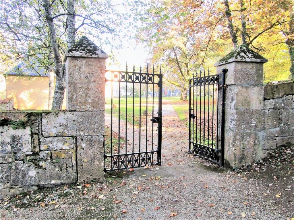 uma velha cerca de pedra com um portão num parque em La Chapelle du Chateau Lagarrigue em Strenquels