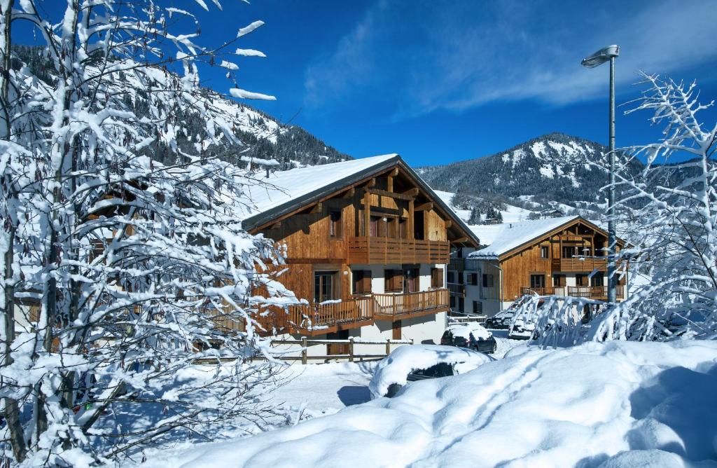 una cabaña de madera en la nieve con una montaña en Résidence Néméa Les Chalets Des Evettes, en Flumet