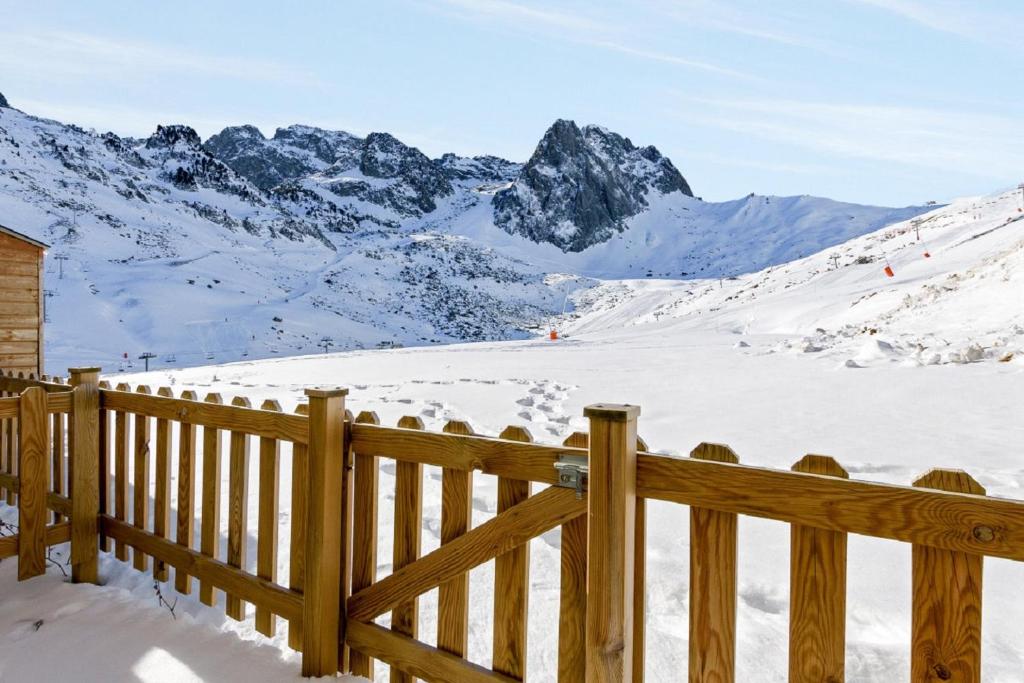 una valla de madera frente a una montaña cubierta de nieve en Residence Le Montana - maeva Home, en La Mongie