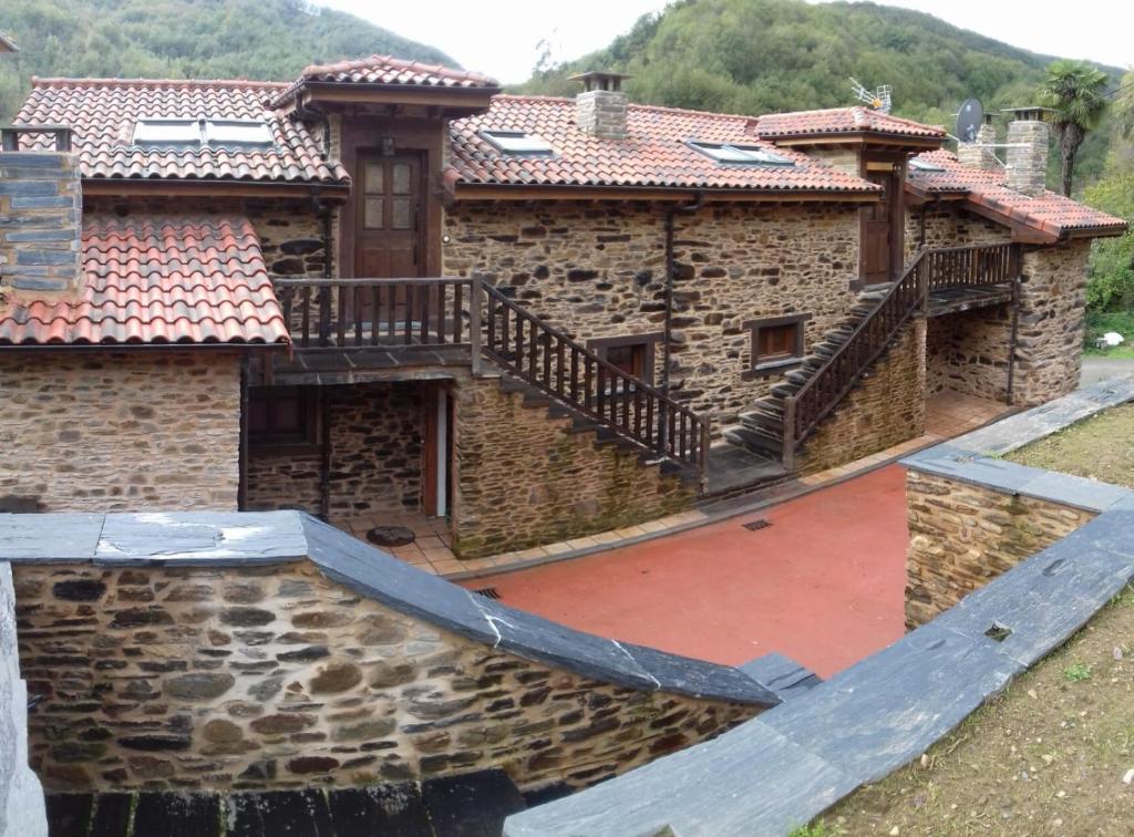 an old stone house with a staircase on it at Apartamentos Rurales Casa Carmen in Pola de Allande