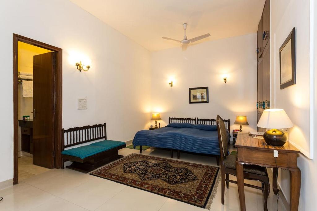 um quarto com uma cama, uma secretária e uma mesa em Eleven Bed & Breakfast em Nova Deli