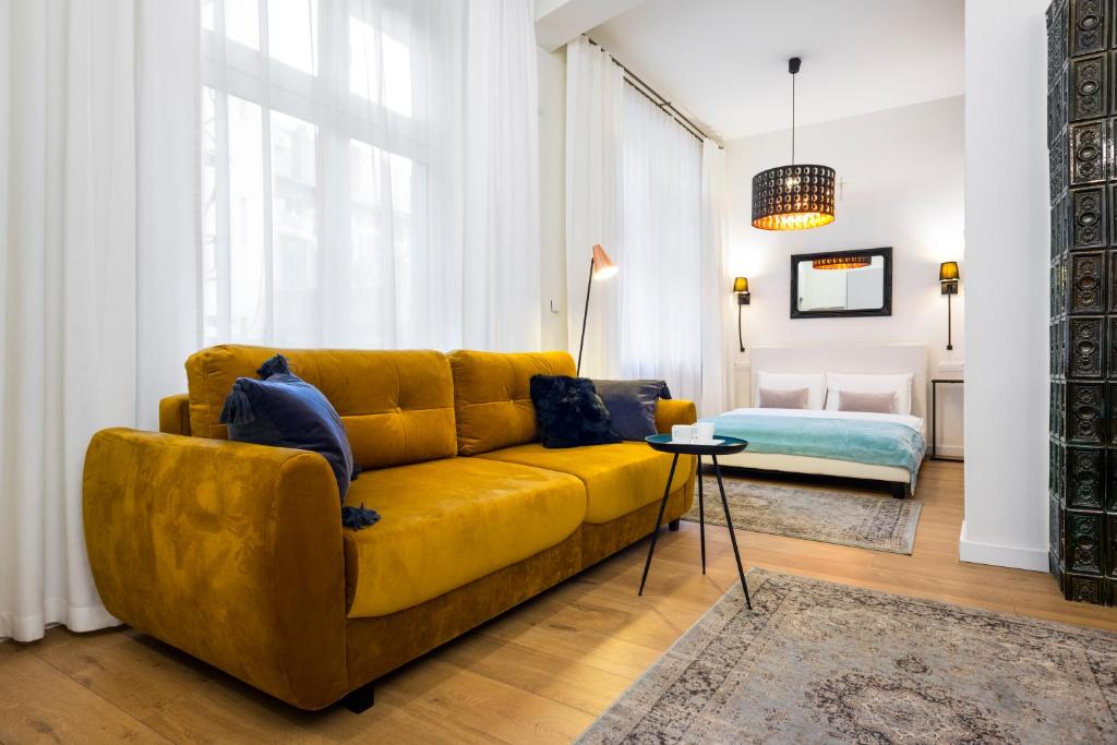 sala de estar con sofá amarillo y cama en Apartament Tenczyńska, en Cracovia