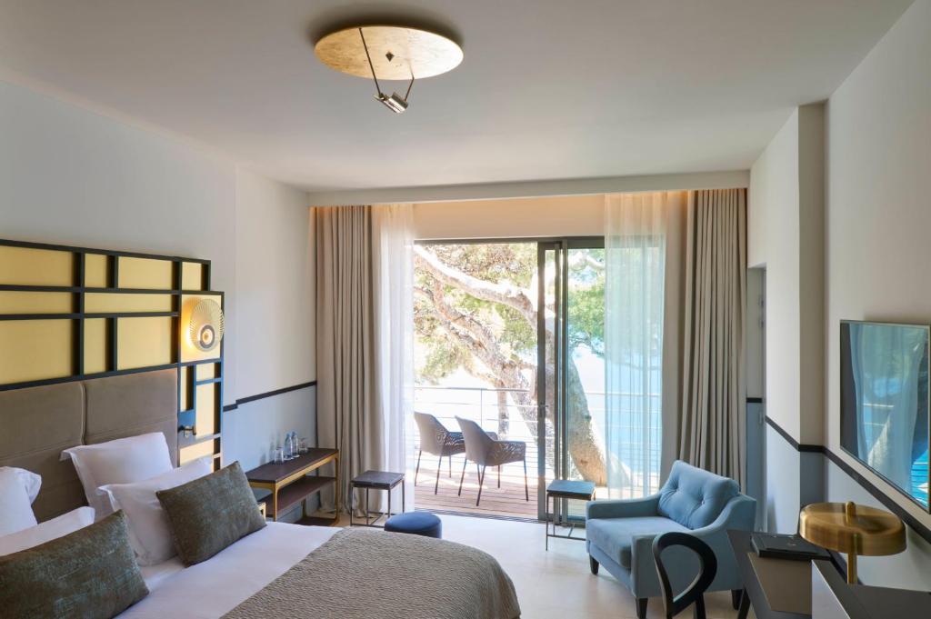 a bedroom with a bed and a sliding glass door at Hôtel Les Roches Blanches Cassis in Cassis