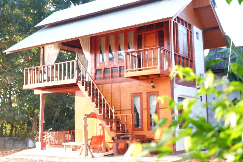 Casa de madera con balcón y escaleras en Pan Fai Homestay, en Nan