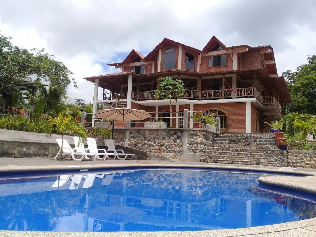 a house with a swimming pool in front of a house at La Casa del Rio B&B in Puyo