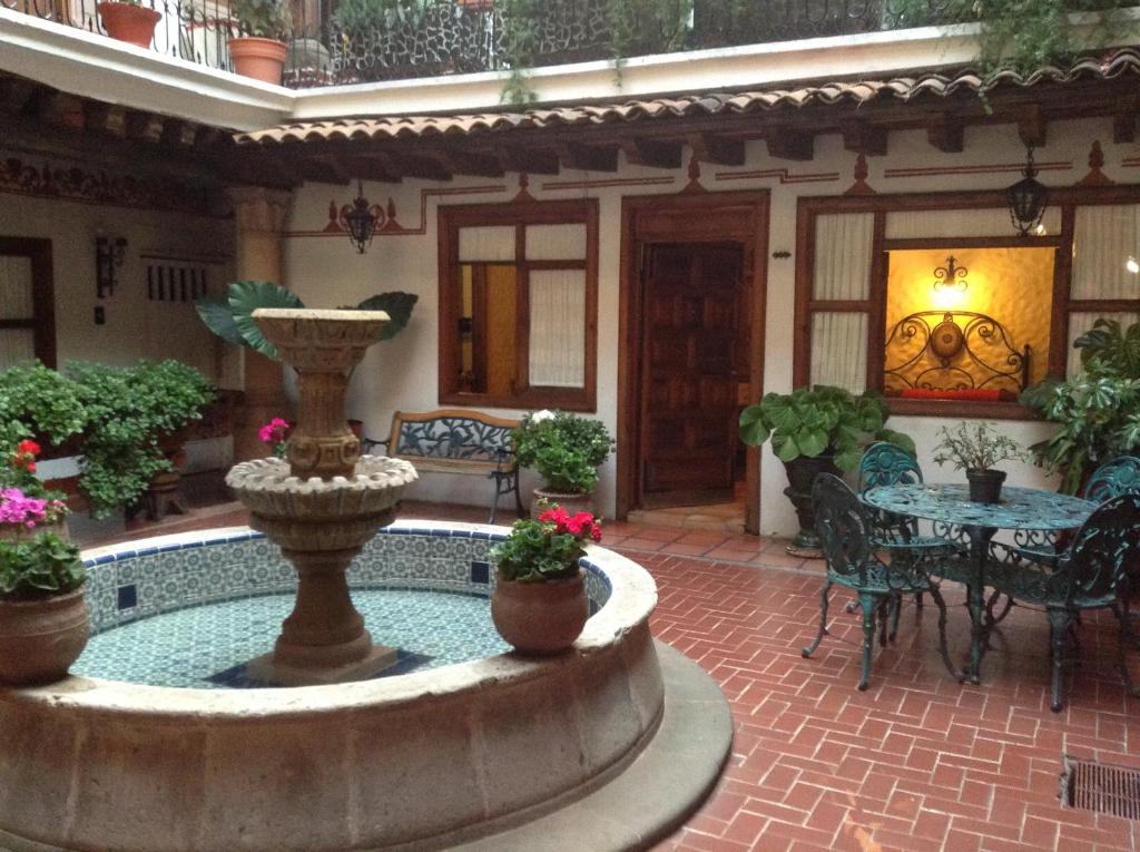une cour avec une fontaine, une table et des chaises dans l'établissement Hotel Los Escudos, à Pátzcuaro