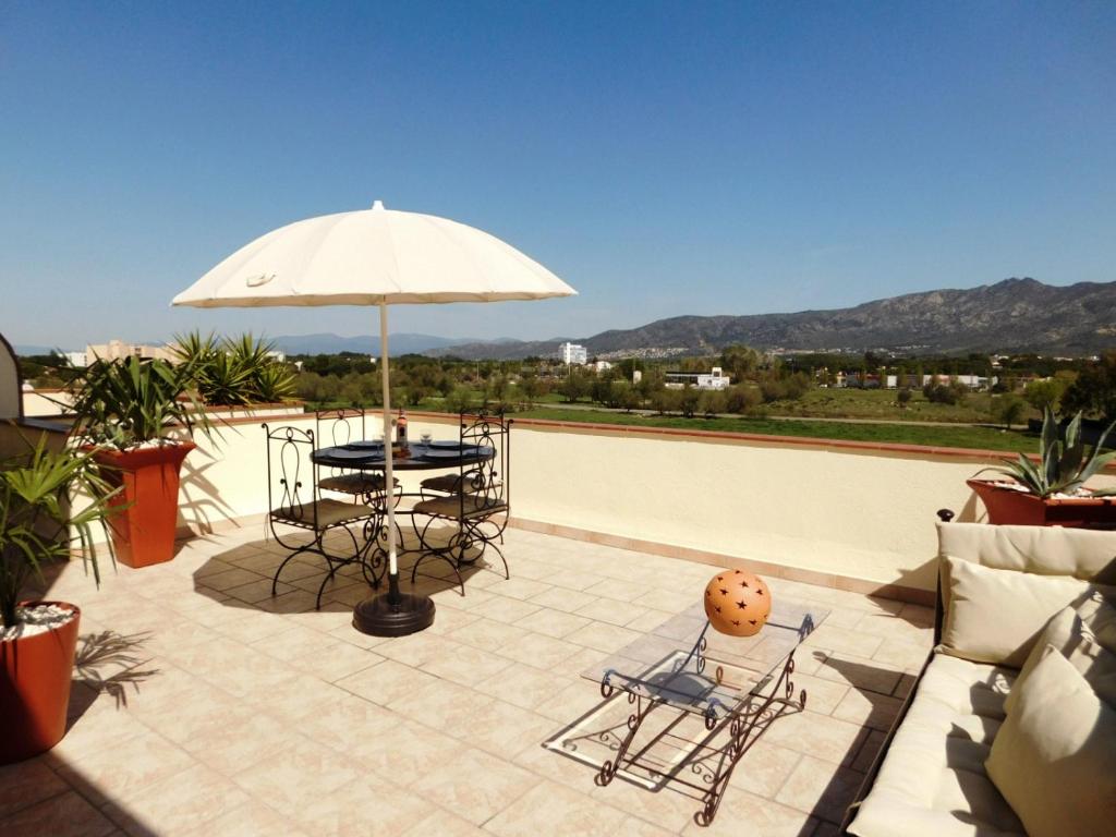 eine Terrasse mit einem Tisch, Stühlen und einem Sonnenschirm in der Unterkunft GMID IMMO Apartamento Lorena in Roses