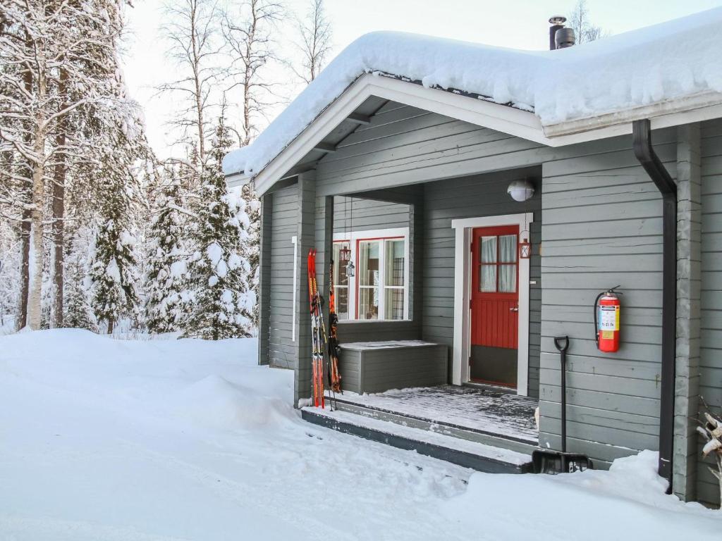 a gray house with a red door in the snow at Holiday Home Yllästokka 7 by Interhome in Ylläsjärvi