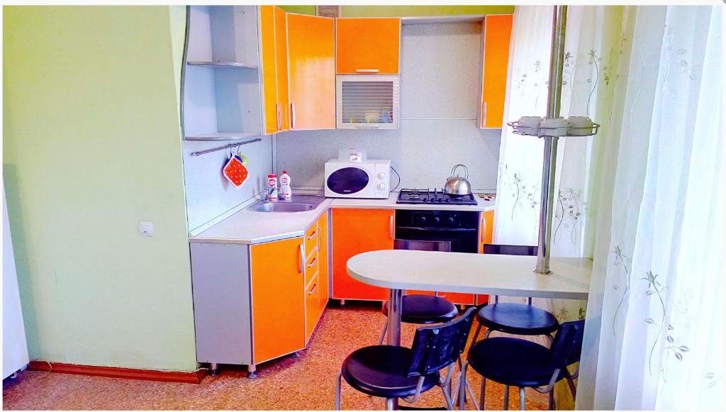 ニジネカムスクにあるАпартаменты в Центре на Химиков 44の小さなキッチン(オレンジ色のキャビネット、テーブル付)