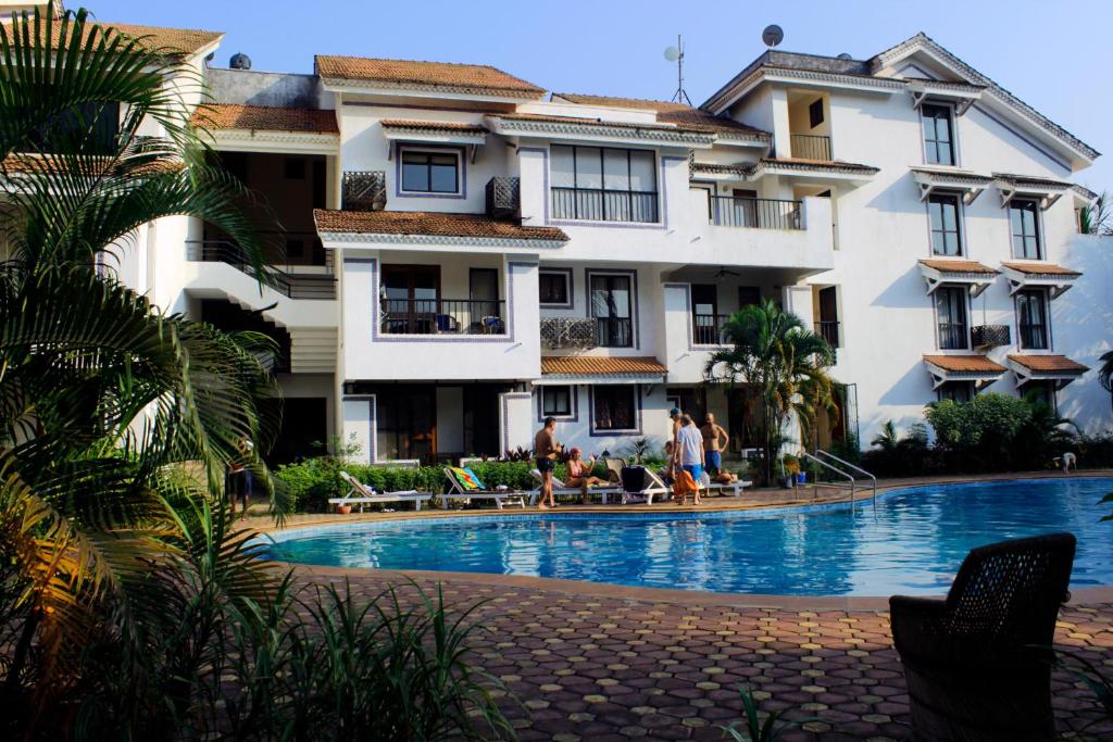 ein Hotel mit einem Pool vor einem Gebäude in der Unterkunft Susegad Suites Goa Apartments & Villas Riviera Hermitage Arpora in Arpora