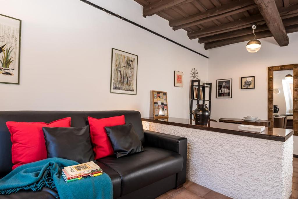 sala de estar con sofá de cuero negro y almohadas rojas en Al Cedro, en Roma