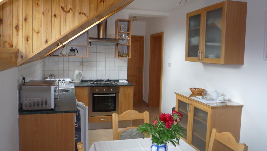 a kitchen with wooden cabinets and a table with flowers on it at Apartmány Gráf in Chýně