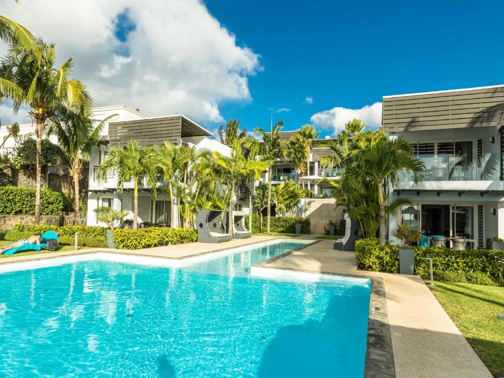 una piscina di fronte a una casa con palme di AH 5-Seafront,Premium,Luxurious,Serviced Apartment a Triolet