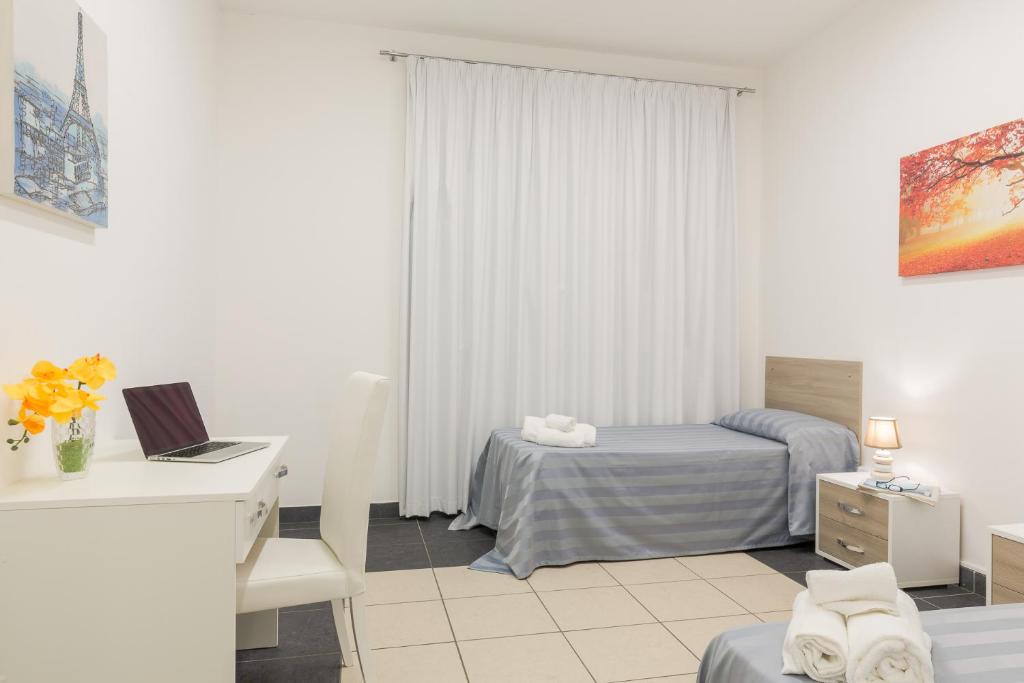 a bedroom with a bed and a desk with a laptop at Casa per Ferie Don Orione Palermo in Palermo
