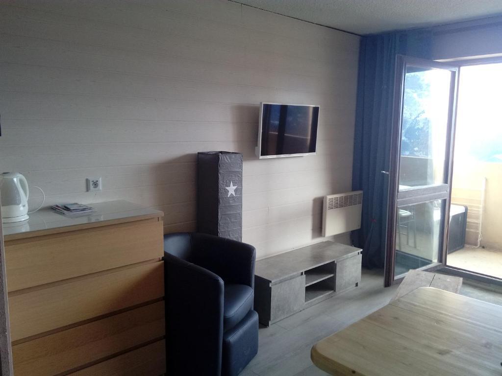a room with a chair and a tv on the wall at auris en oisans, vue sur le massif des ecrins in Auris