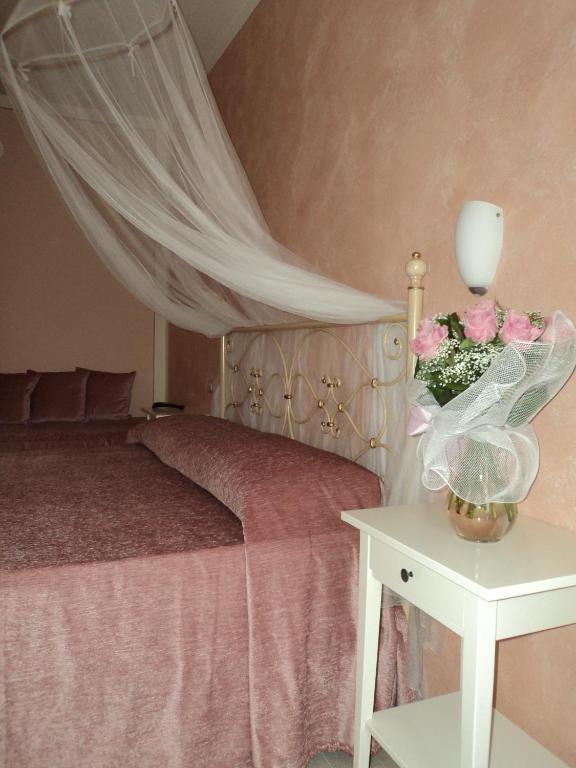 a bedroom with a bed and a table with flowers at Bed&Breakfast Giardini di Corte in Toscolano Maderno