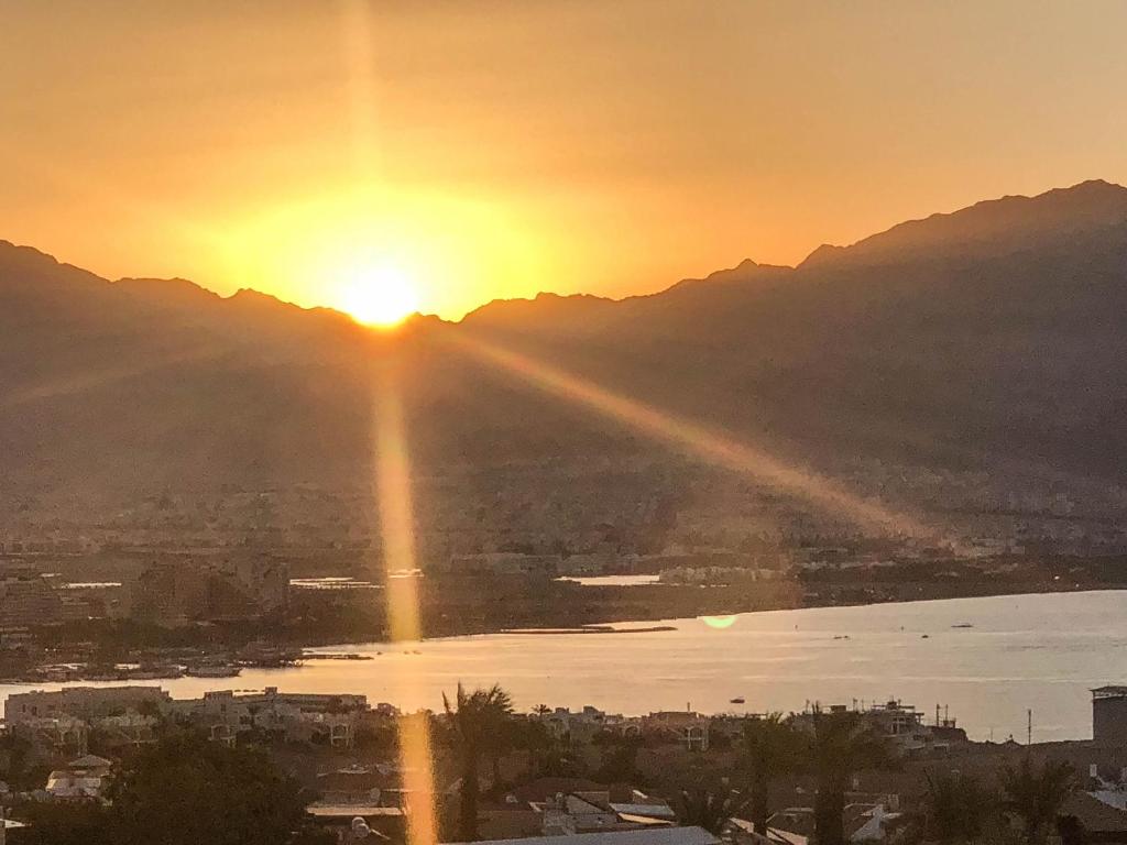 a sunset over a city and a body of water at Sea View Coral Suite in Eilat