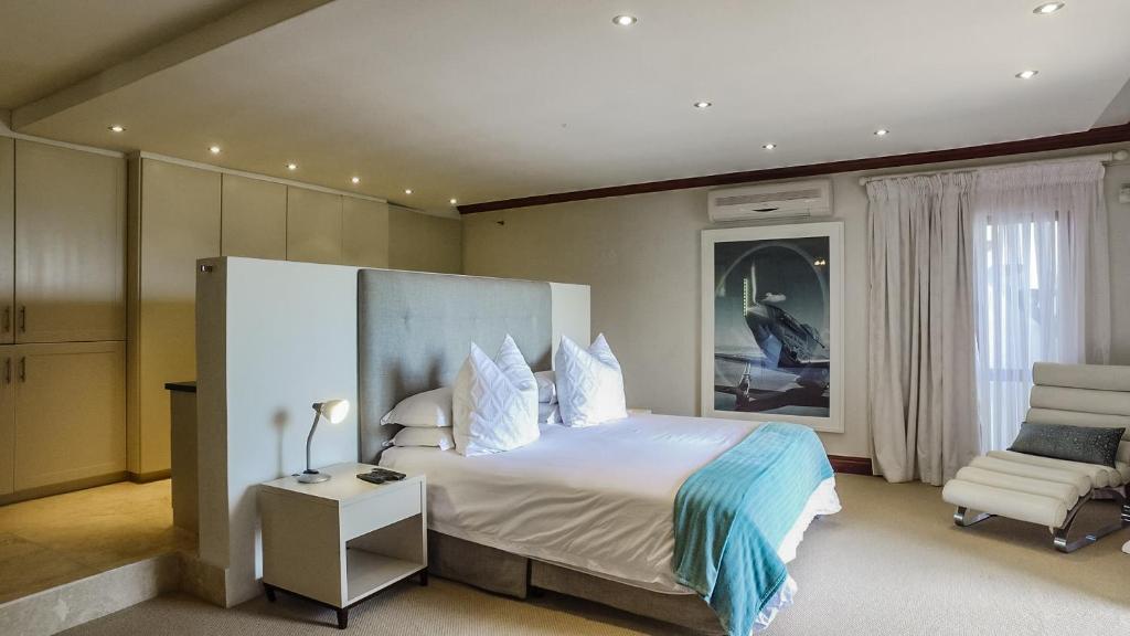 una camera da letto con un letto grande e una sedia di Knysna Pearl View Guest House a Knysna
